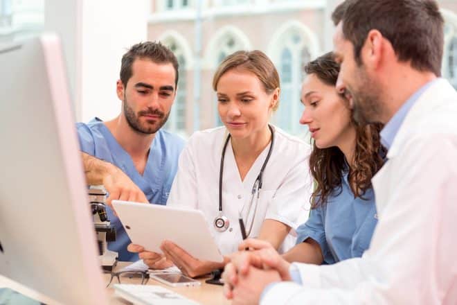 Nurse and healthcare team reviewing information together on a tablet